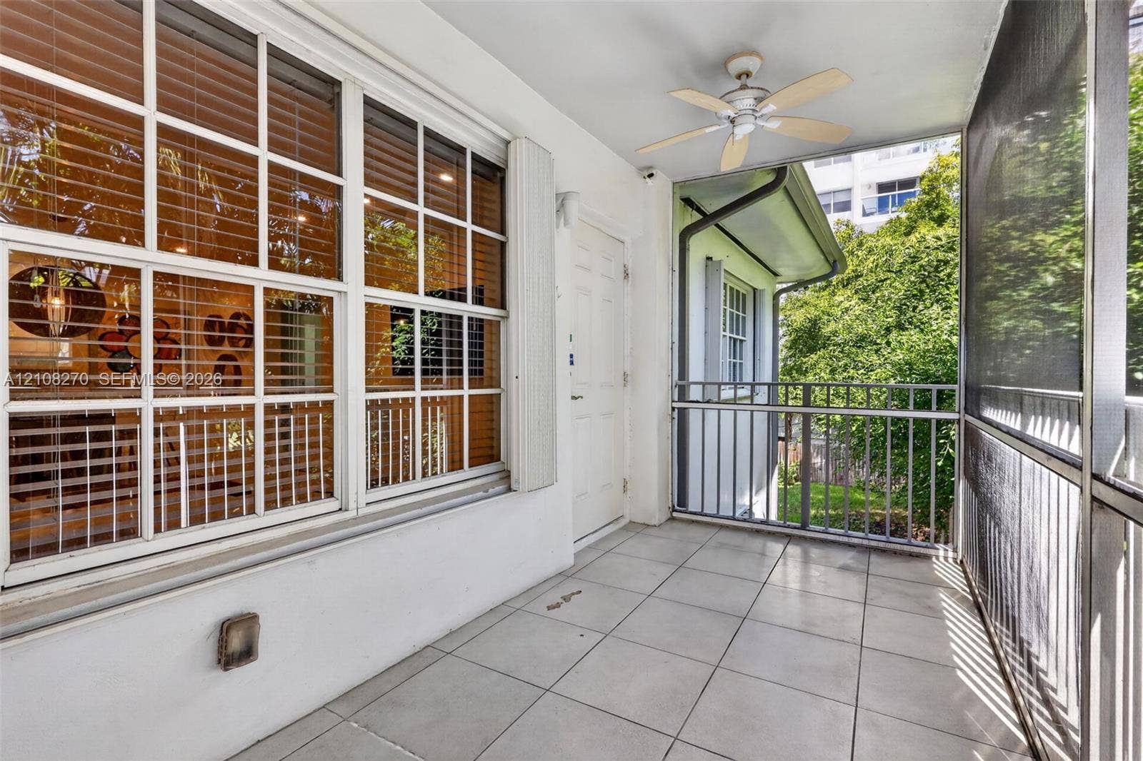1125 99th Street, #12, Bay Harbor Islands, FL 33154 Screened-in balcony featuring tile flooring, a ceiling fan, and metal railings