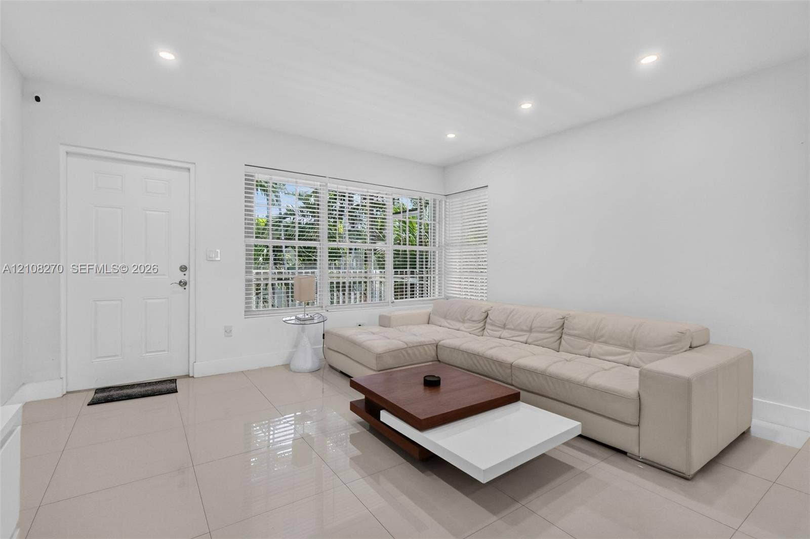 1125 99th Street, #12, Bay Harbor Islands, FL 33154 Large-format neutral tile flooring, recessed ceiling lighting, and expansive windows fitted with horizontal blinds