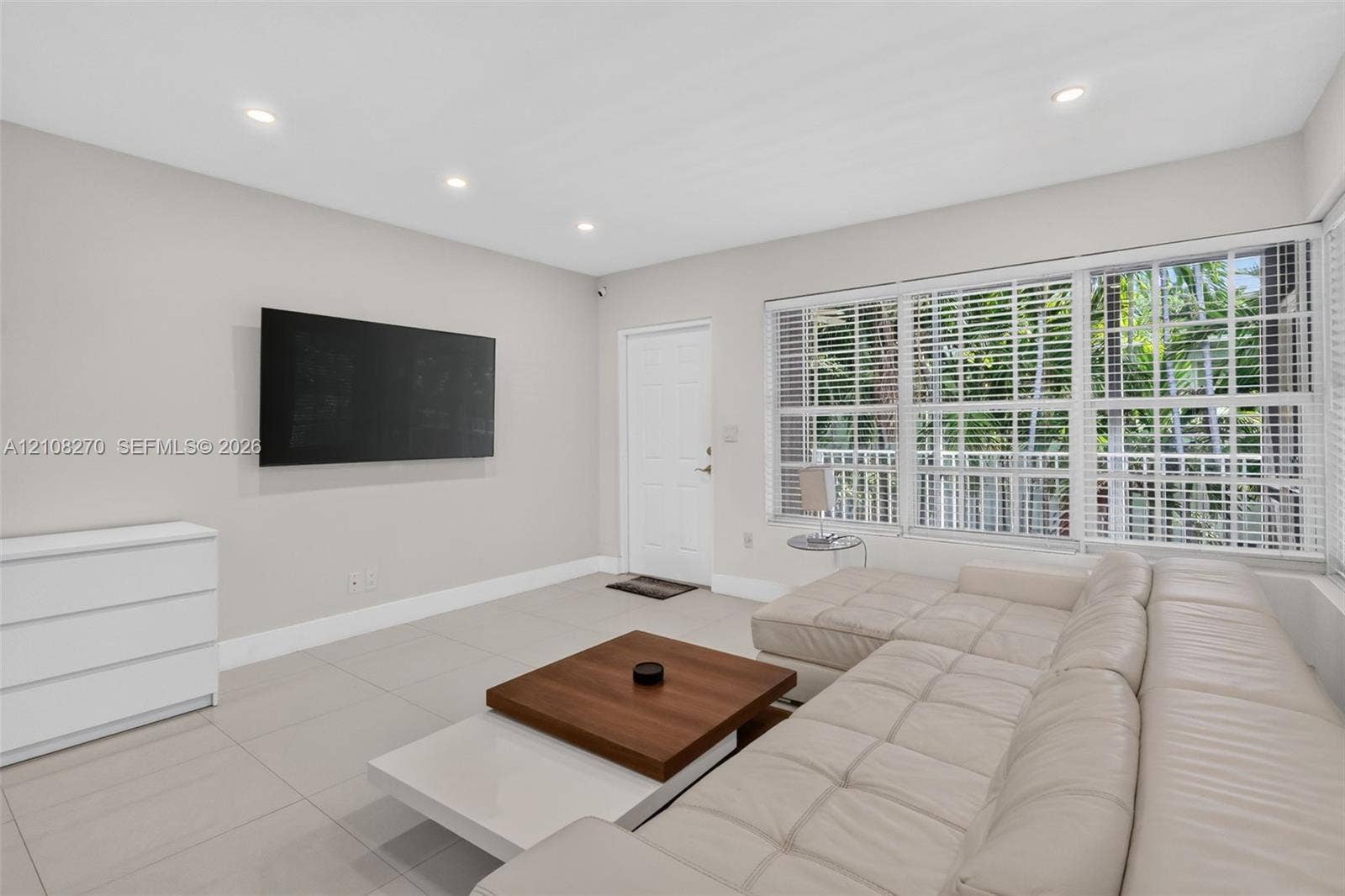 1125 99th Street, #12, Bay Harbor Islands, FL 33154 Neutral-toned interior featuring large-format ceramic tile flooring, recessed lighting, and expansive multi-pane windows with horizontal blinds