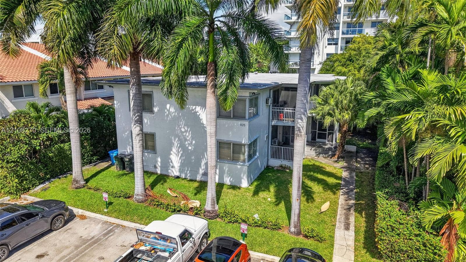 1125 99th Street, #12, Bay Harbor Islands, FL 33154 Two-story exterior featuring a light-toned smooth finish, multi-pane windows, and private railed balconies, situated on a lot with mature palm trees