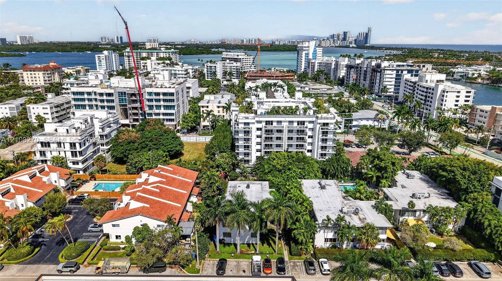 1125 99th Street, #12, Bay Harbor Islands, FL 33154 Aerial perspective of a multi-residential enclave featuring orange-tiled rooflines, manicured palm landscaping, asphalt surface parking, and perimeter hedging