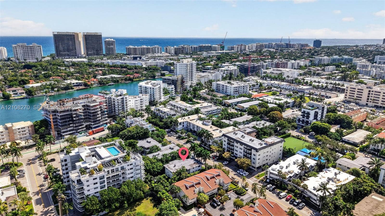 1125 99th Street, #12, Bay Harbor Islands, FL 33154 Aerial perspective of a multi-story residential building featuring a flat roofline, integrated parking area, mature landscaping, and positioning within a coastal urban setting