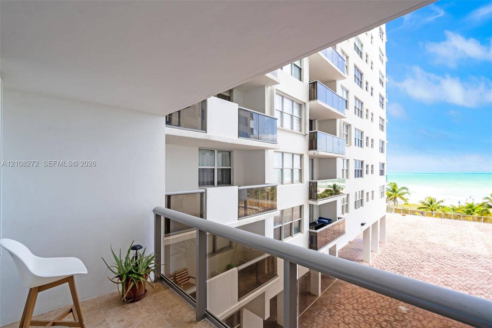 Private balcony with tiled flooring and metal railing overlooking the shoreline and coastal scenery