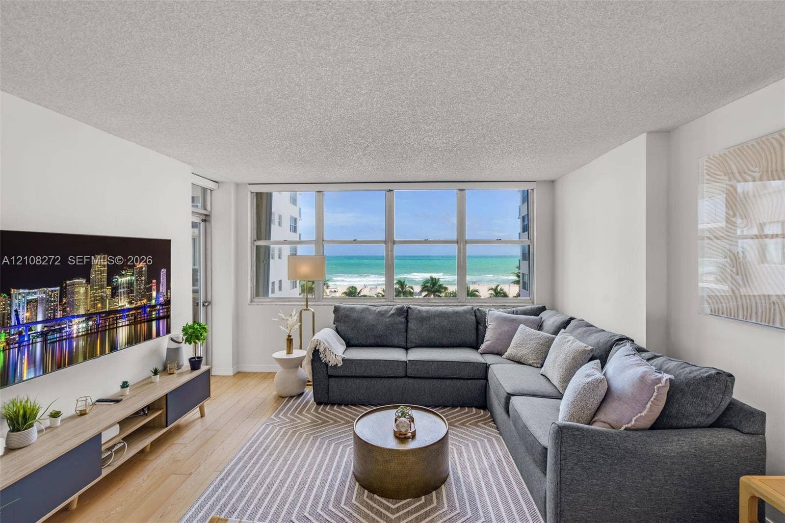 Expansive multi-pane window featuring coastal scenery, wood-finish flooring, and neutral wall tones