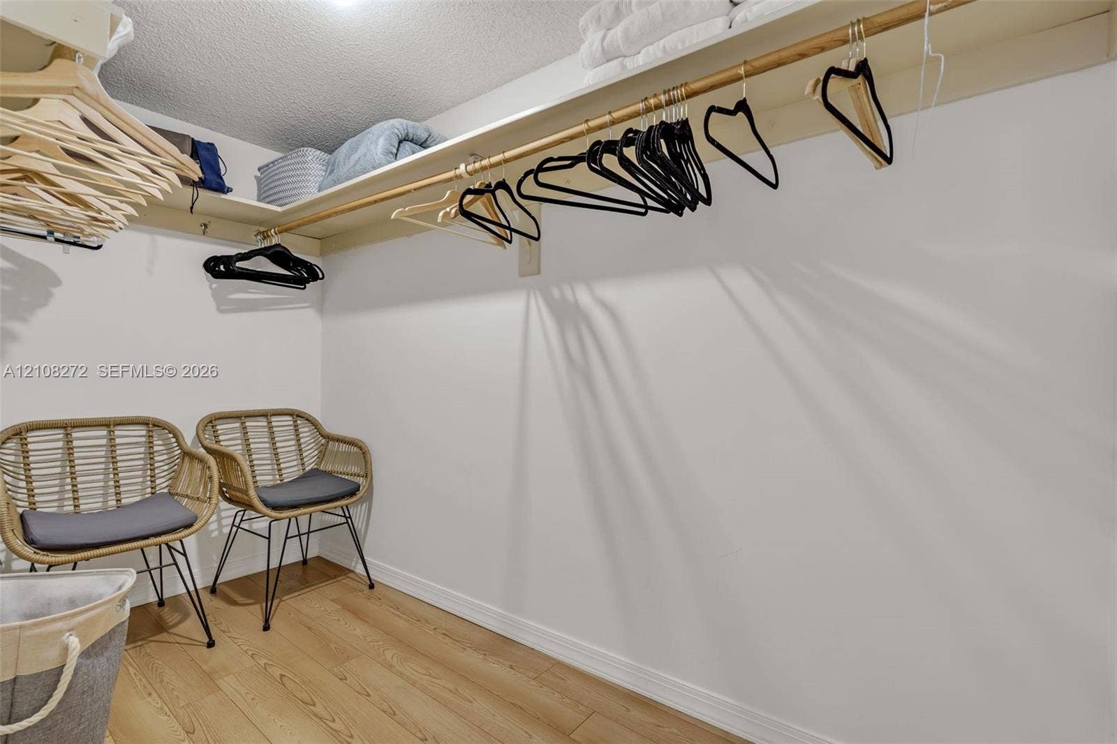 Walk-in closet featuring wood-finish flooring and integrated wall-to-wall shelving with a hanging rod