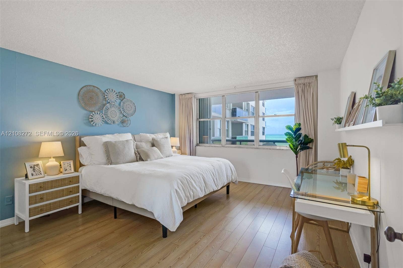 Spacious room featuring wood-finish flooring, a blue accent wall, and a large multi-pane window