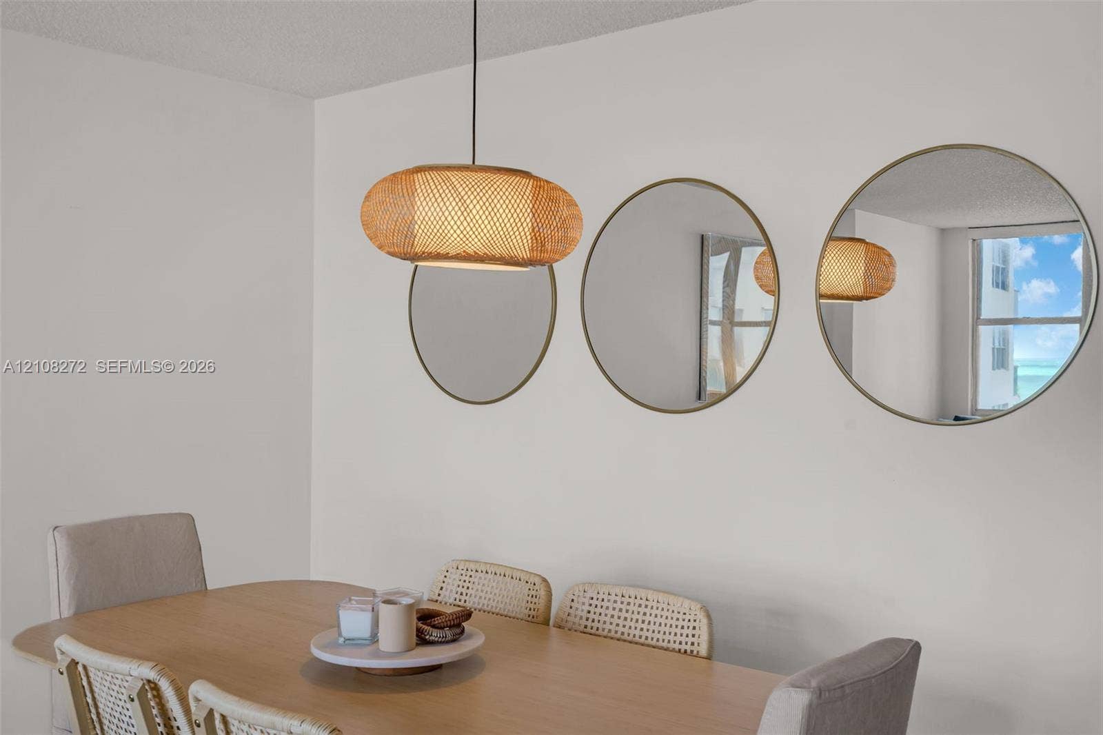 Woven rattan pendant light fixture and three circular wall-mounted mirrors with metallic frames