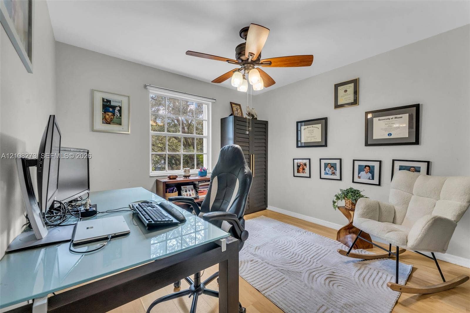 Room featuring wood-finish flooring, a multi-light ceiling fan, and a grid-style window