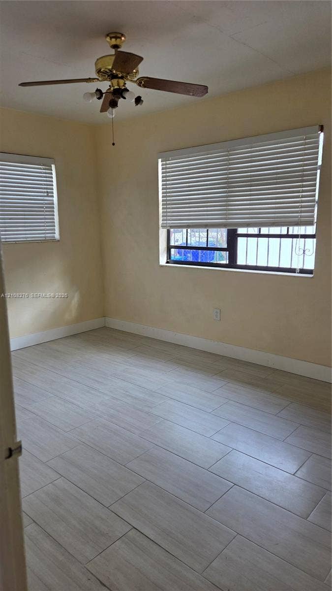 Room featuring wood-finish tile flooring, ceiling fan with light fixture, and horizontal blinds on windows