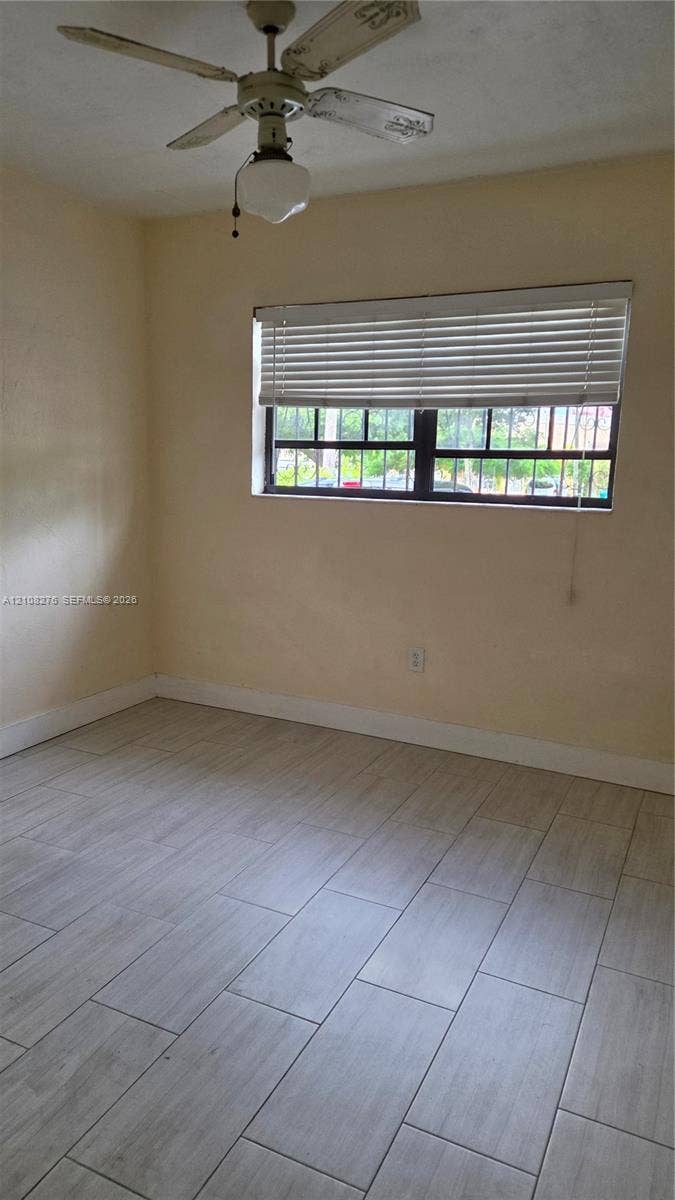 Wood-finish tile flooring, multi-pane window with horizontal blinds, and a ceiling-mounted fan with integrated lighting