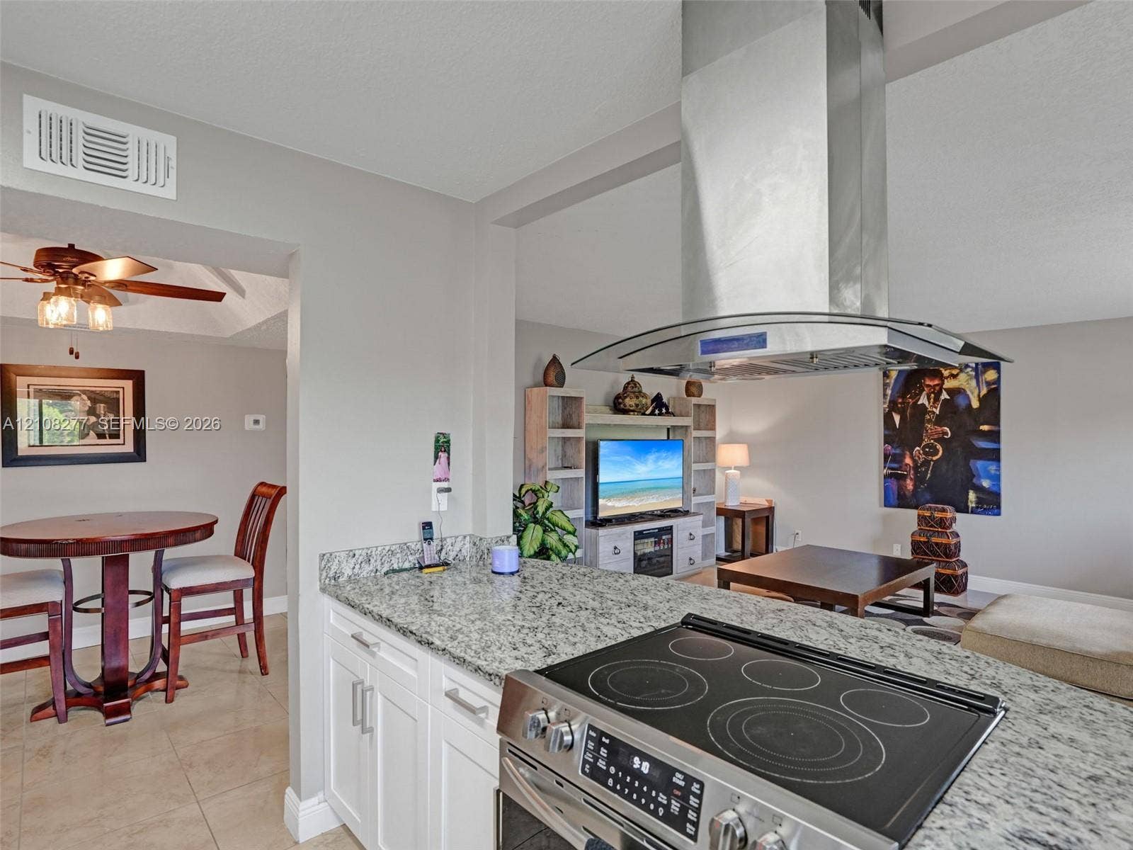 7466 Ashmont Circle, #303, Tamarac, FL 33321 Kitchen featuring a stone countertop peninsula, stainless steel slide-in electric range, and a ceiling-mounted stainless steel chimney-style range hood