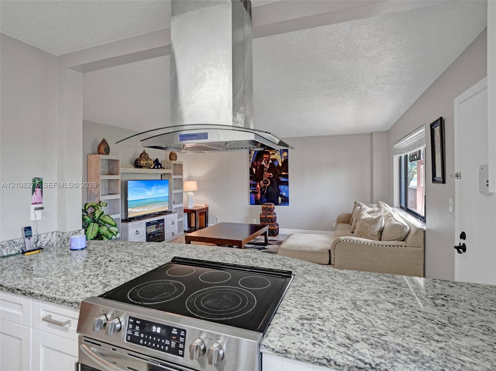 7466 Ashmont Circle, #303, Tamarac, FL 33321 Kitchen featuring stone-finish countertops, stainless steel electric range, island-mounted stainless steel chimney hood, and built-in white cabinetry