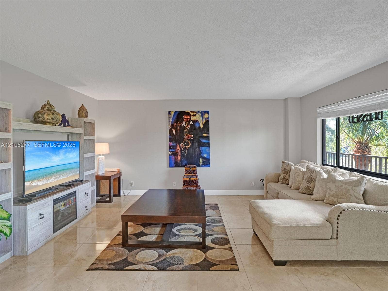 7466 Ashmont Circle, #303, Tamarac, FL 33321 Living area featuring large-format tile flooring, light-toned built-in cabinetry, and a picture window