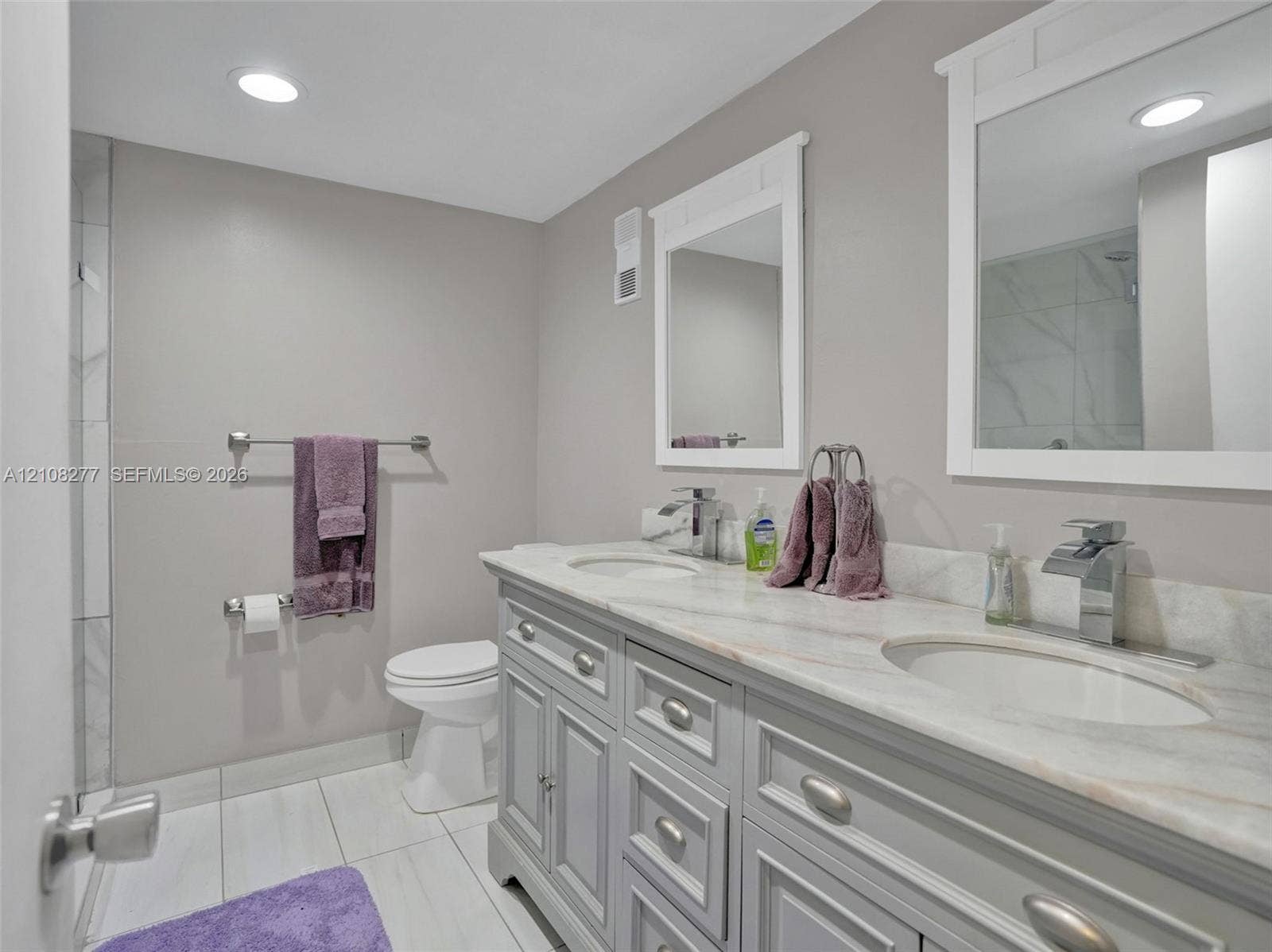 7466 Ashmont Circle, #303, Tamarac, FL 33321 Double vanity featuring stone-finish countertops, undermount sinks, polished chrome faucets, and shaker-style cabinetry with dual wall-mounted mirrors