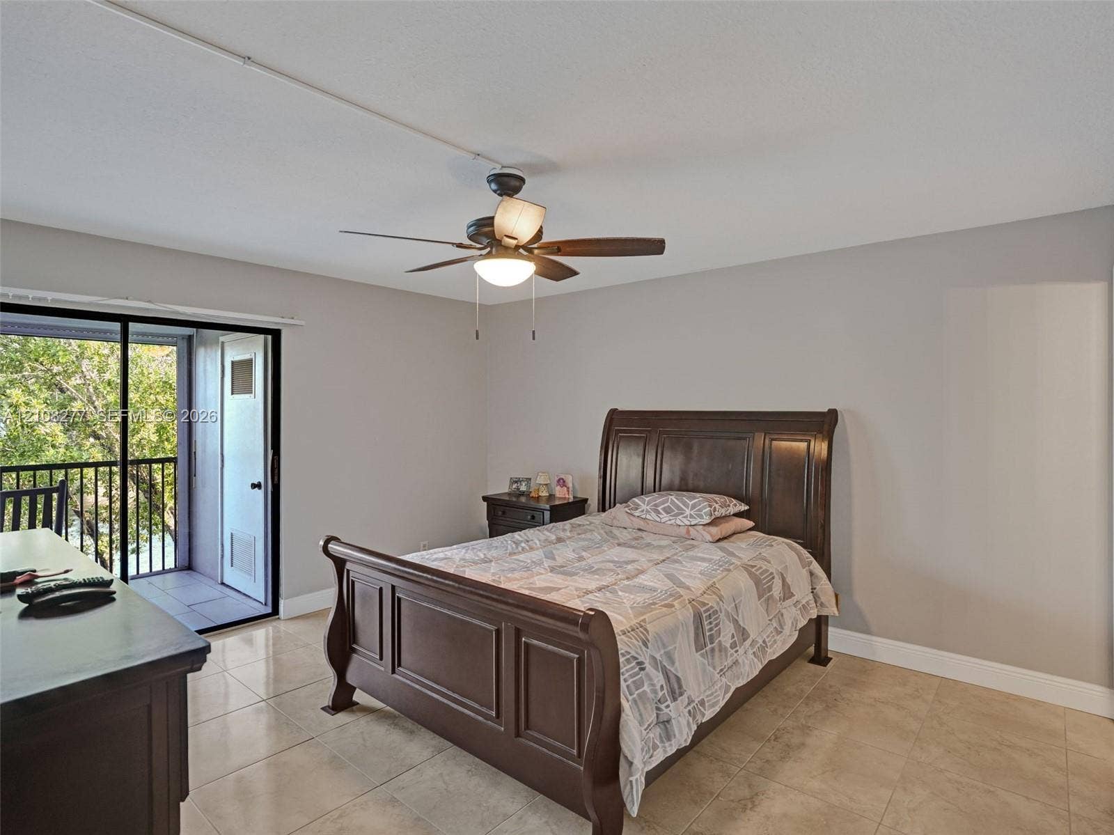 7466 Ashmont Circle, #303, Tamarac, FL 33321 Large-format tile flooring, ceiling fan with integrated lighting, and a sliding glass door providing access to a private balcony