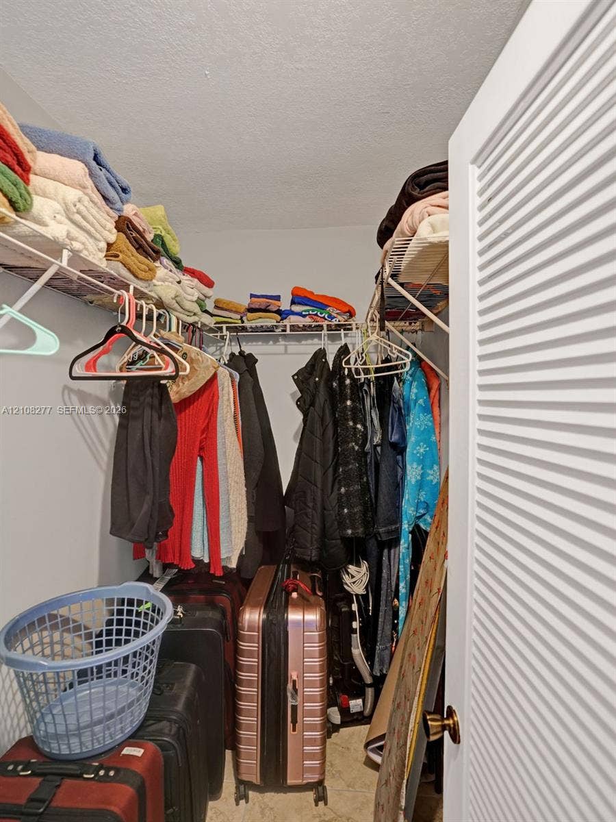 7466 Ashmont Circle, #303, Tamarac, FL 33321 Storage space featuring ventilated wire shelving, neutral wall tones, and a louvered entry door with metallic hardware