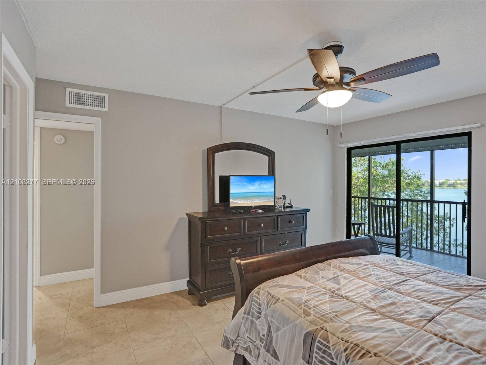 7466 Ashmont Circle, #303, Tamarac, FL 33321 Ceramic tile flooring, ceiling fan with integrated lighting, and glass sliding doors opening to a screened balcony