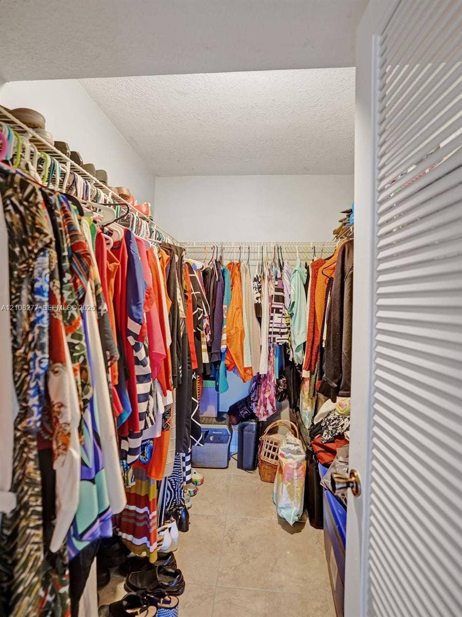 7466 Ashmont Circle, #303, Tamarac, FL 33321 Walk-in closet featuring floor-to-ceiling metal wire shelving and neutral tile flooring