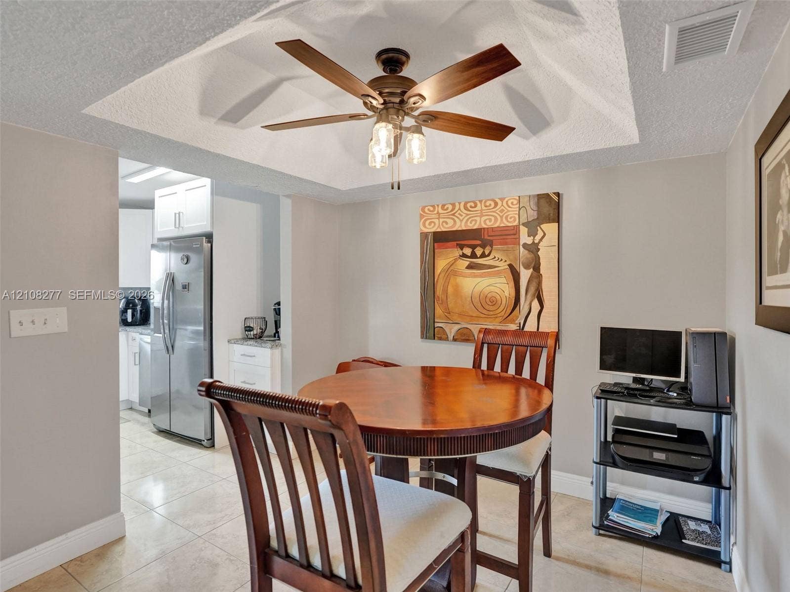 7466 Ashmont Circle, #303, Tamarac, FL 33321 Tray ceiling with a central multi-blade ceiling fan and integrated light fixture, featuring tile flooring throughout