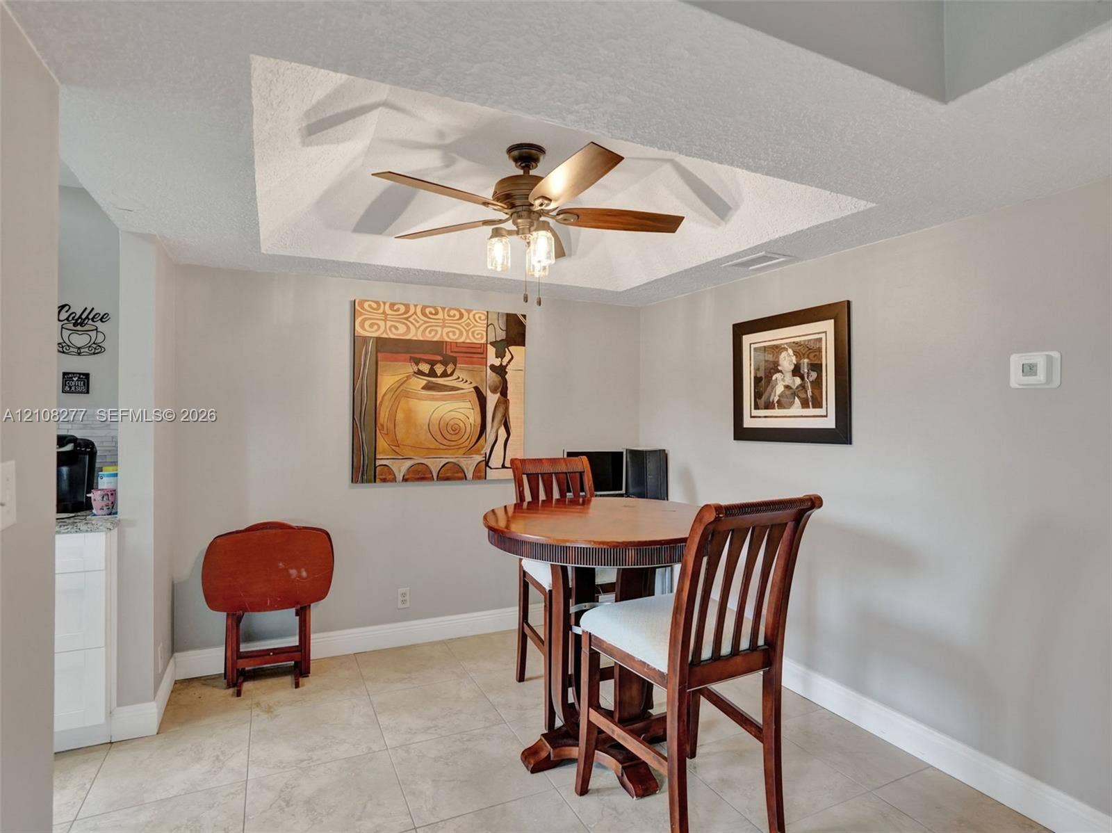 7466 Ashmont Circle, #303, Tamarac, FL 33321 Tray ceiling featuring a central five-blade ceiling fan with integrated lighting and neutral ceramic tile flooring
