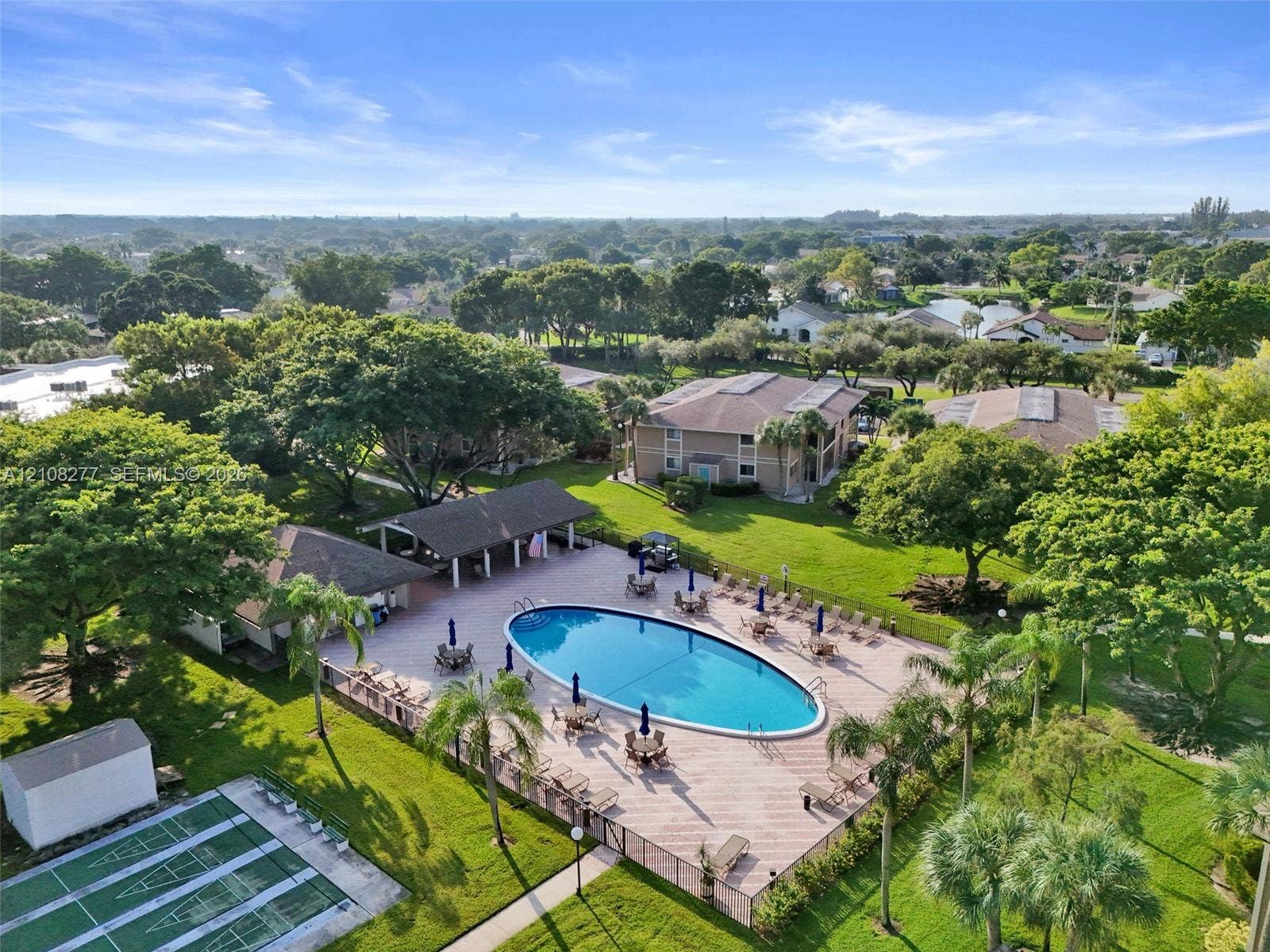 7466 Ashmont Circle, #303, Tamarac, FL 33321 Community amenities featuring a fenced pool, covered pavilion, and hard-surface court situated within landscaped grounds