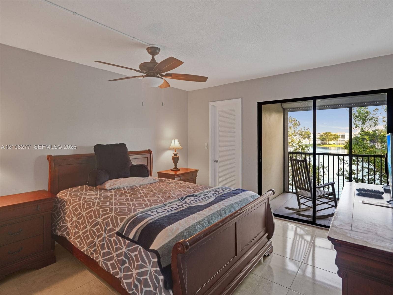 7466 Ashmont Circle, #303, Tamarac, FL 33321 Spacious room featuring polished tile flooring, a multi-blade ceiling fan, and sliding glass doors opening to a private balcony with water scenery