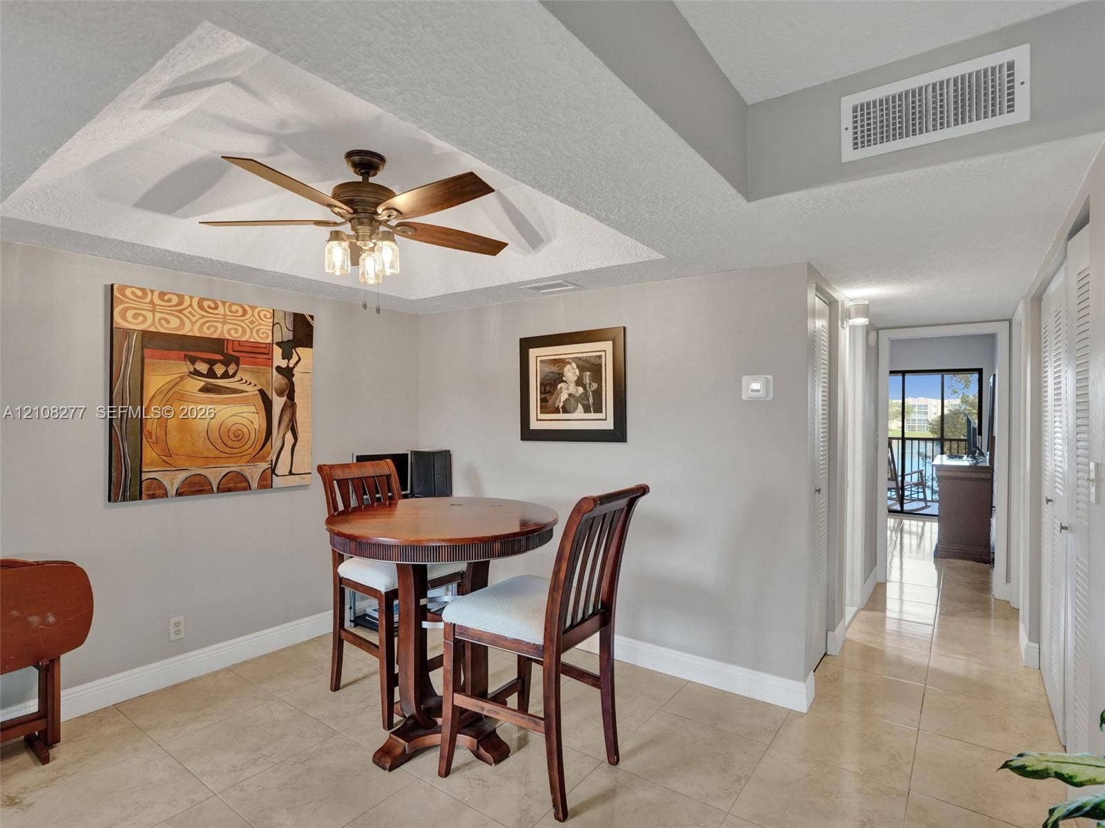 7466 Ashmont Circle, #303, Tamarac, FL 33321 Tray ceiling featuring a central five-blade ceiling fan with integrated light fixture, neutral wall finishes, and large-format tile flooring