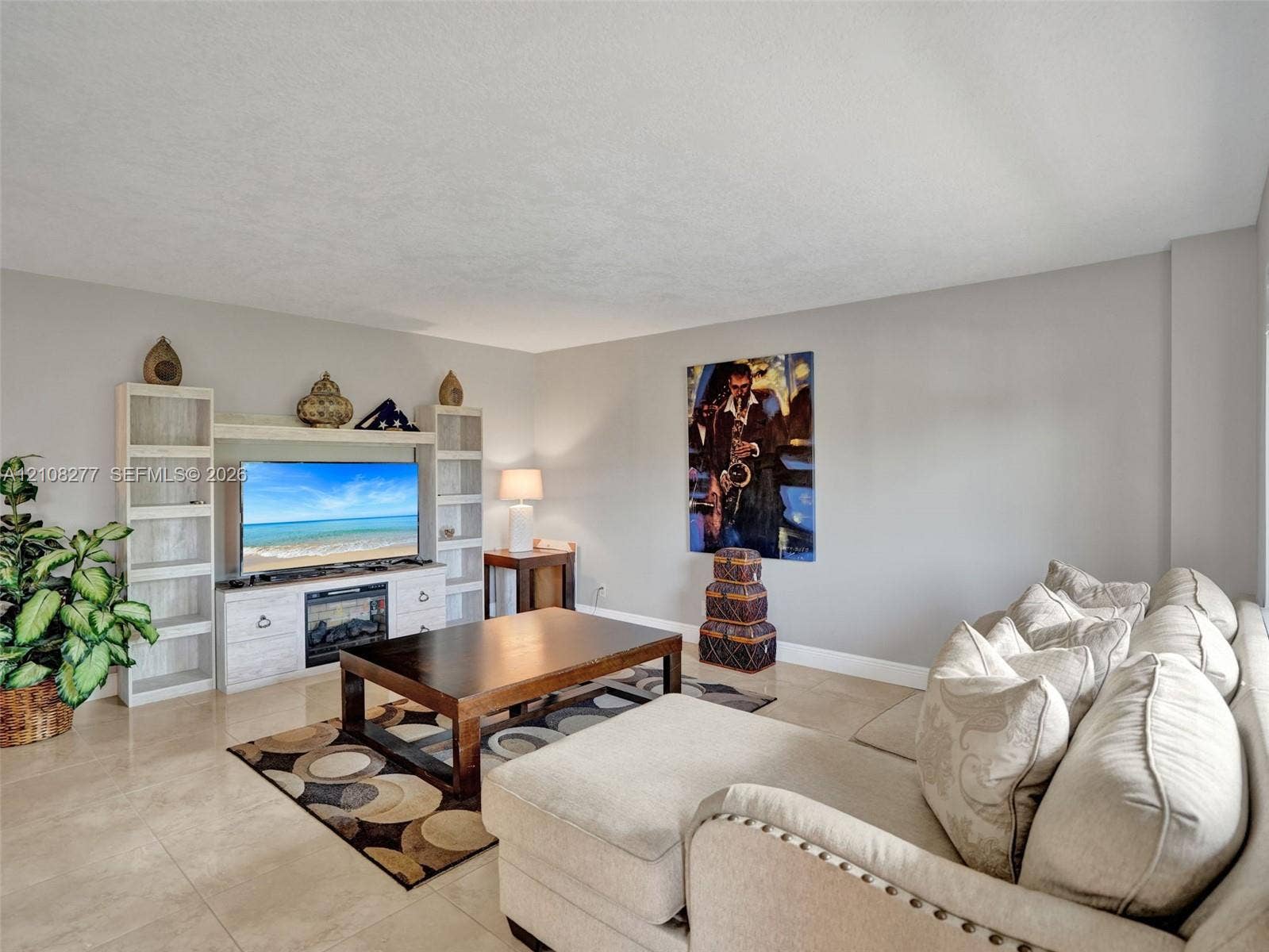 7466 Ashmont Circle, #303, Tamarac, FL 33321 Living area featuring light-toned tile flooring, neutral wall paint, and built-in cabinetry surrounding an integrated electric fireplace