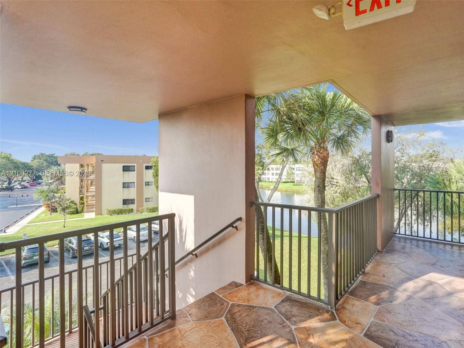 7466 Ashmont Circle, #303, Tamarac, FL 33321 Covered exterior landing with stone-pattern flooring, metal railings, and a wall-mounted handrail