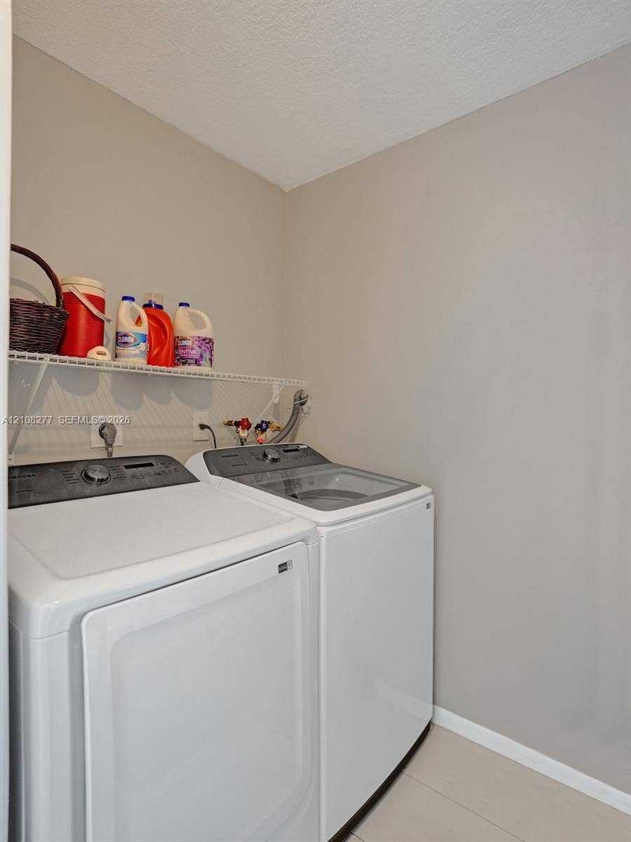 7466 Ashmont Circle, #303, Tamarac, FL 33321 Dedicated laundry space featuring neutral wall paint, tile flooring, and wall-mounted wire shelving