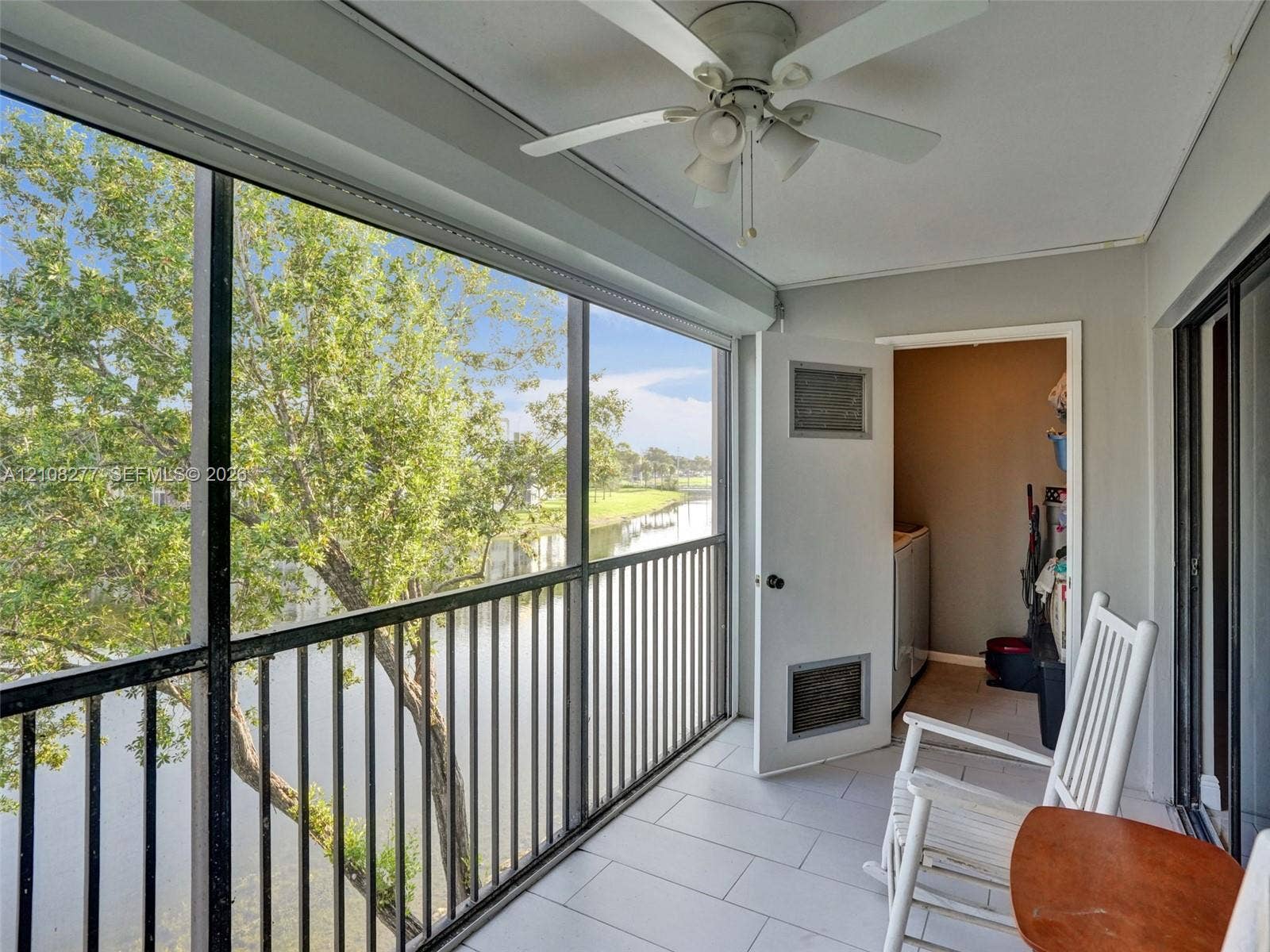 7466 Ashmont Circle, #303, Tamarac, FL 33321 Screened-in balcony featuring tile flooring, a ceiling fan with integrated lighting, and a metal railing