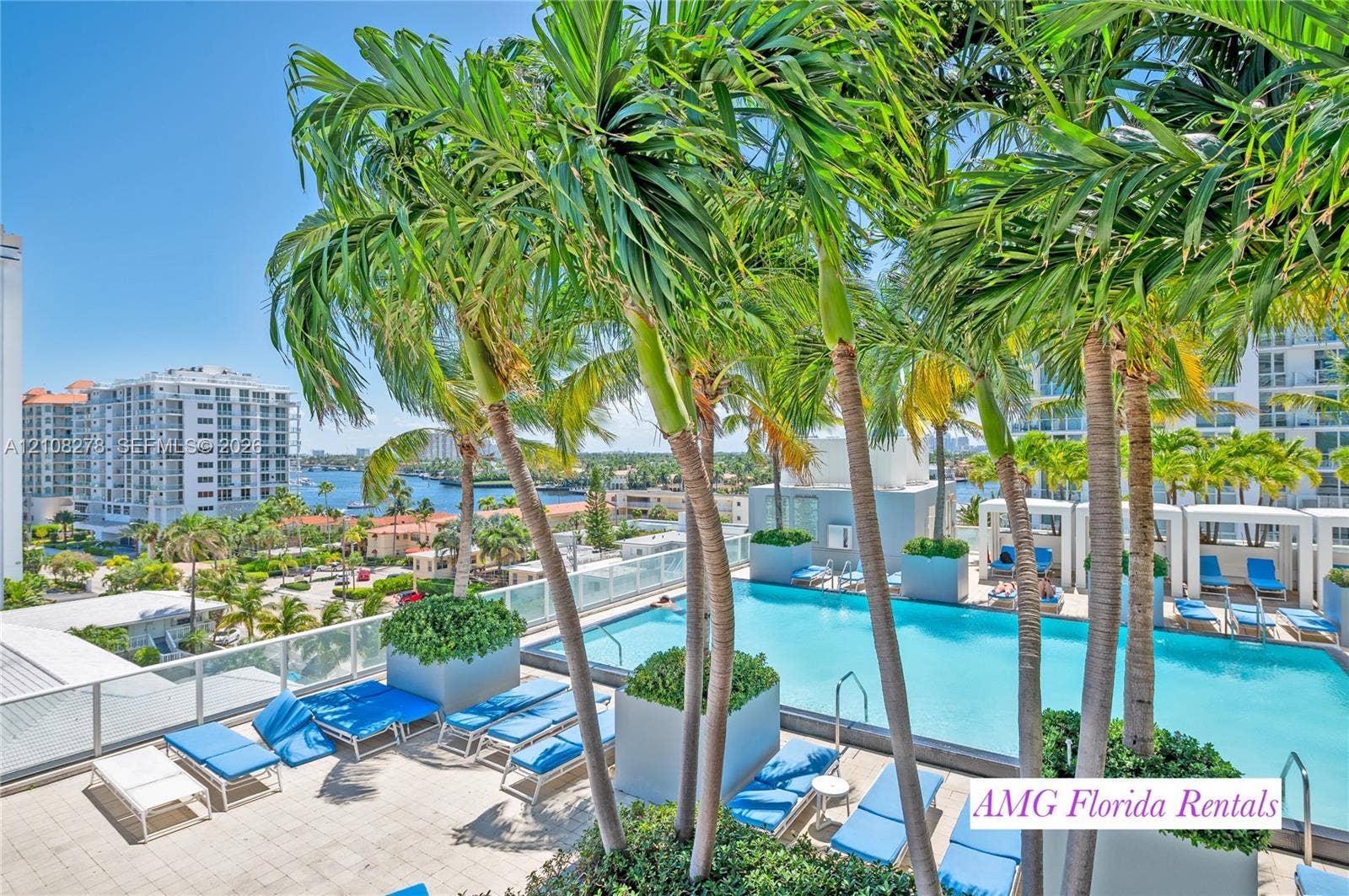 3101 Bayshore Drive, #701, Fort Lauderdale, FL 33304 Elevated swimming pool featuring a tile deck, glass panel perimeter railing, built-in planters, and palm tree landscaping