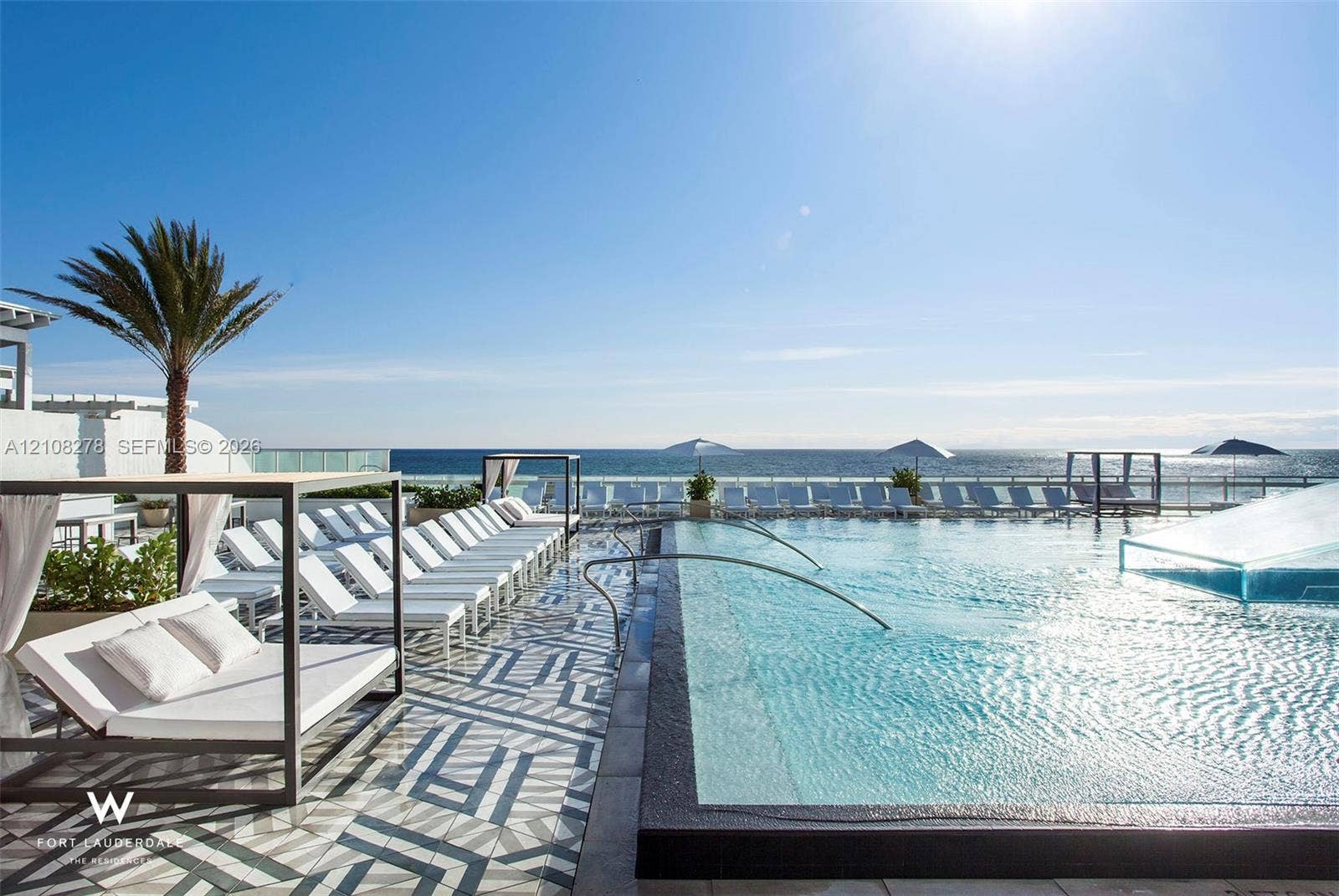 3101 Bayshore Drive, #701, Fort Lauderdale, FL 33304 Infinity-edge swimming pool featuring a patterned tile deck, metal-framed structures, and a glass-paneled perimeter railing