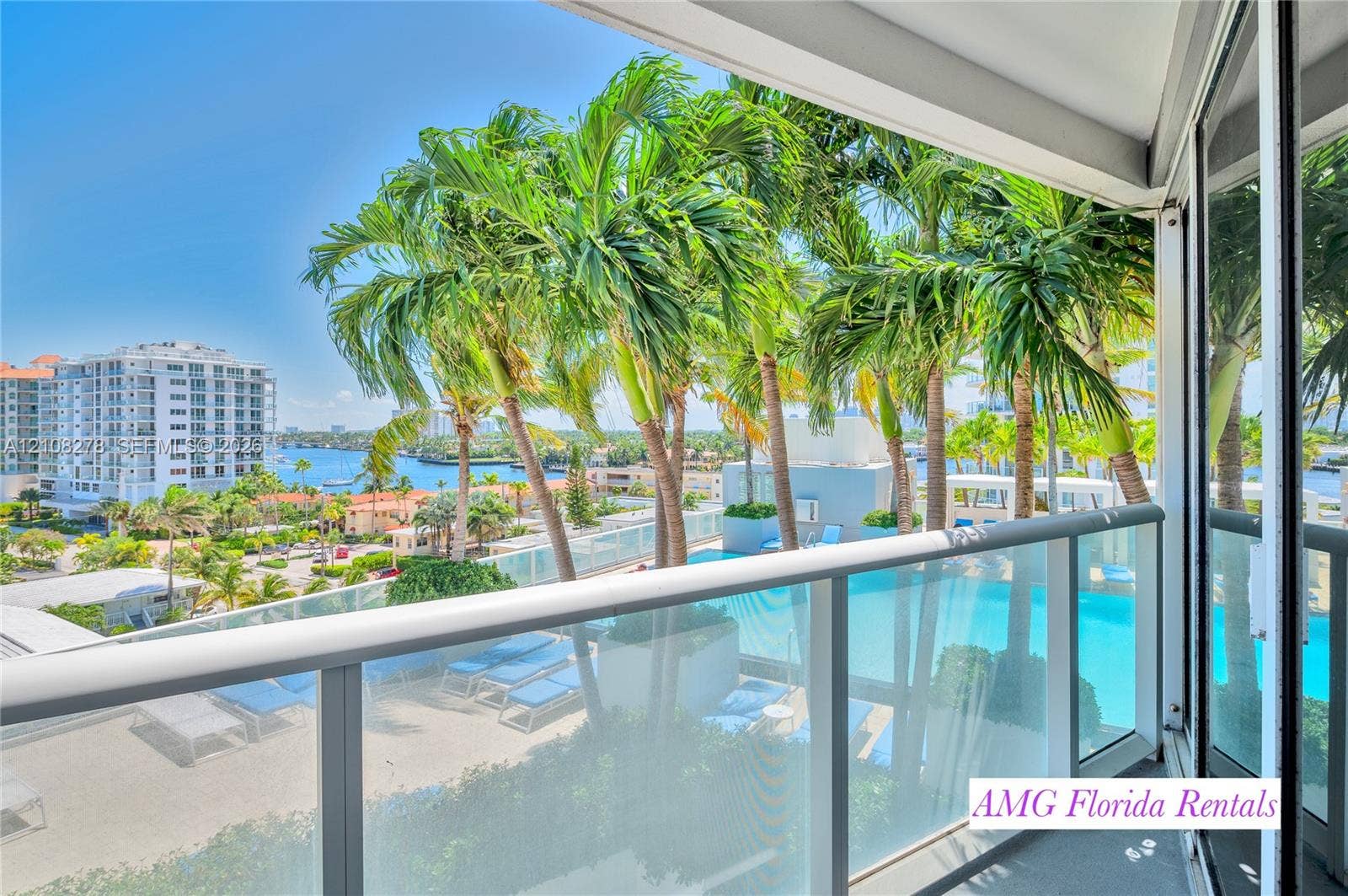 3101 Bayshore Drive, #701, Fort Lauderdale, FL 33304 Private balcony with glass panel railing overlooking a swimming pool, mature palm trees, and coastal waterway