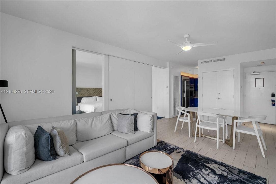 3101 Bayshore Drive, #701, Fort Lauderdale, FL 33304 Open-concept interior featuring wood-finish flooring, white sliding partition doors, and a ceiling-mounted light fixture with integrated fan