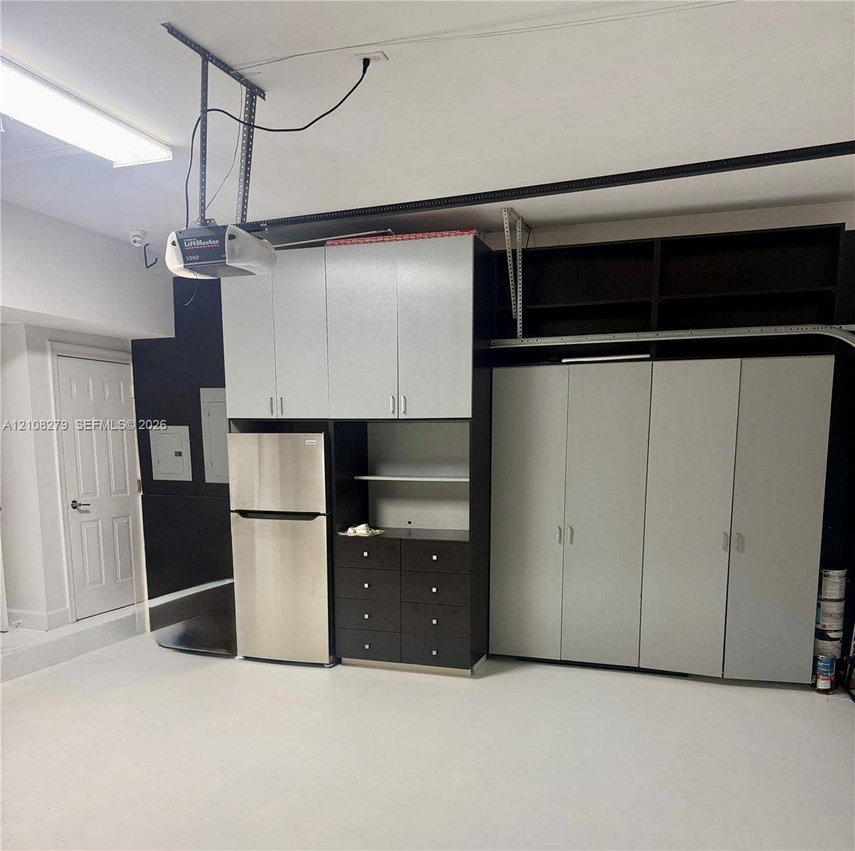 19424 39th Avenue, Sunny Isles Beach, Sunny Isles Beach, FL 33160 Garage featuring extensive built-in cabinetry, integrated shelving, an inset stainless steel refrigerator, and overhead fluorescent lighting