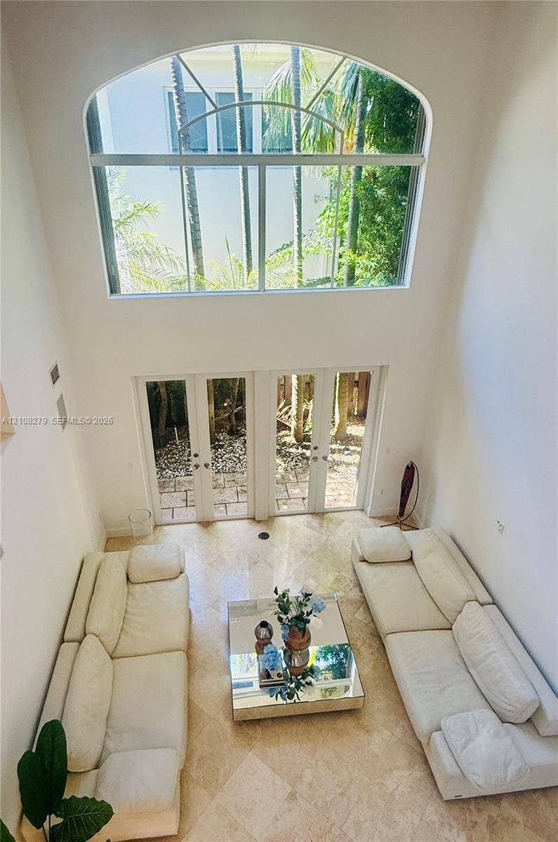 19424 39th Avenue, Sunny Isles Beach, Sunny Isles Beach, FL 33160 Double-height room featuring vaulted ceilings, a large arched window, and dual glass-paned doors with stone tile flooring
