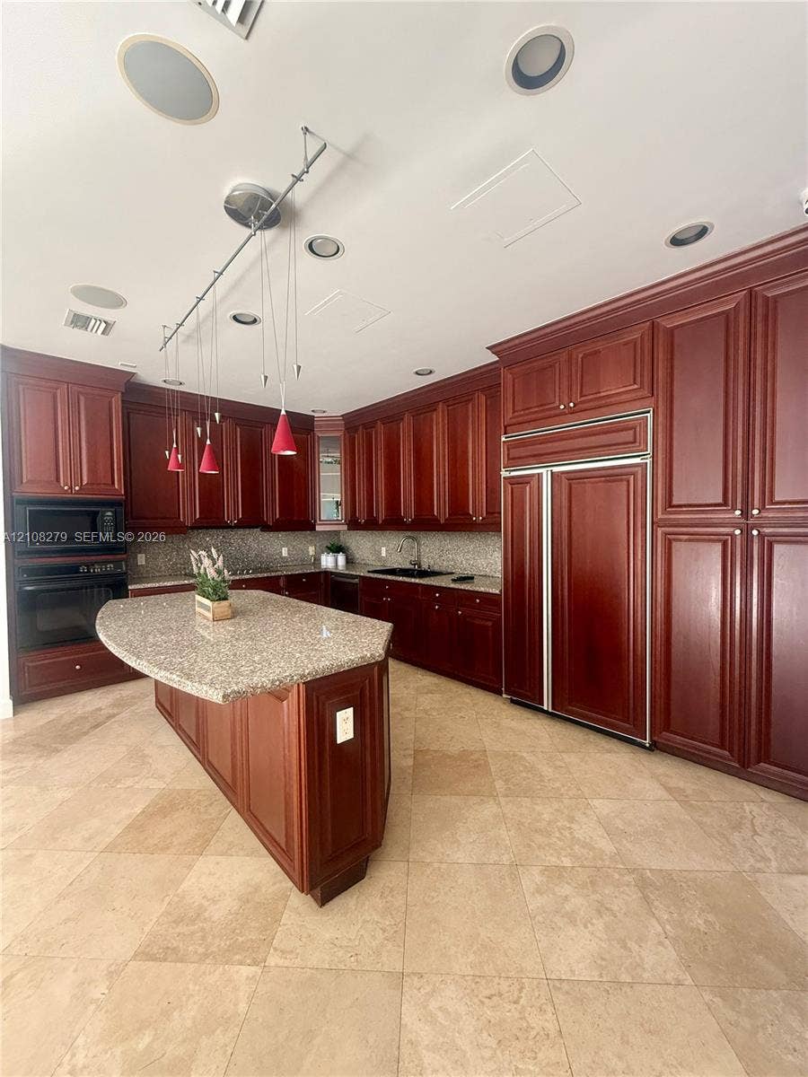 19424 39th Avenue, Sunny Isles Beach, Sunny Isles Beach, FL 33160 Kitchen featuring stained cabinetry, stone countertops, central island, integrated refrigerator, and recessed ceiling lighting