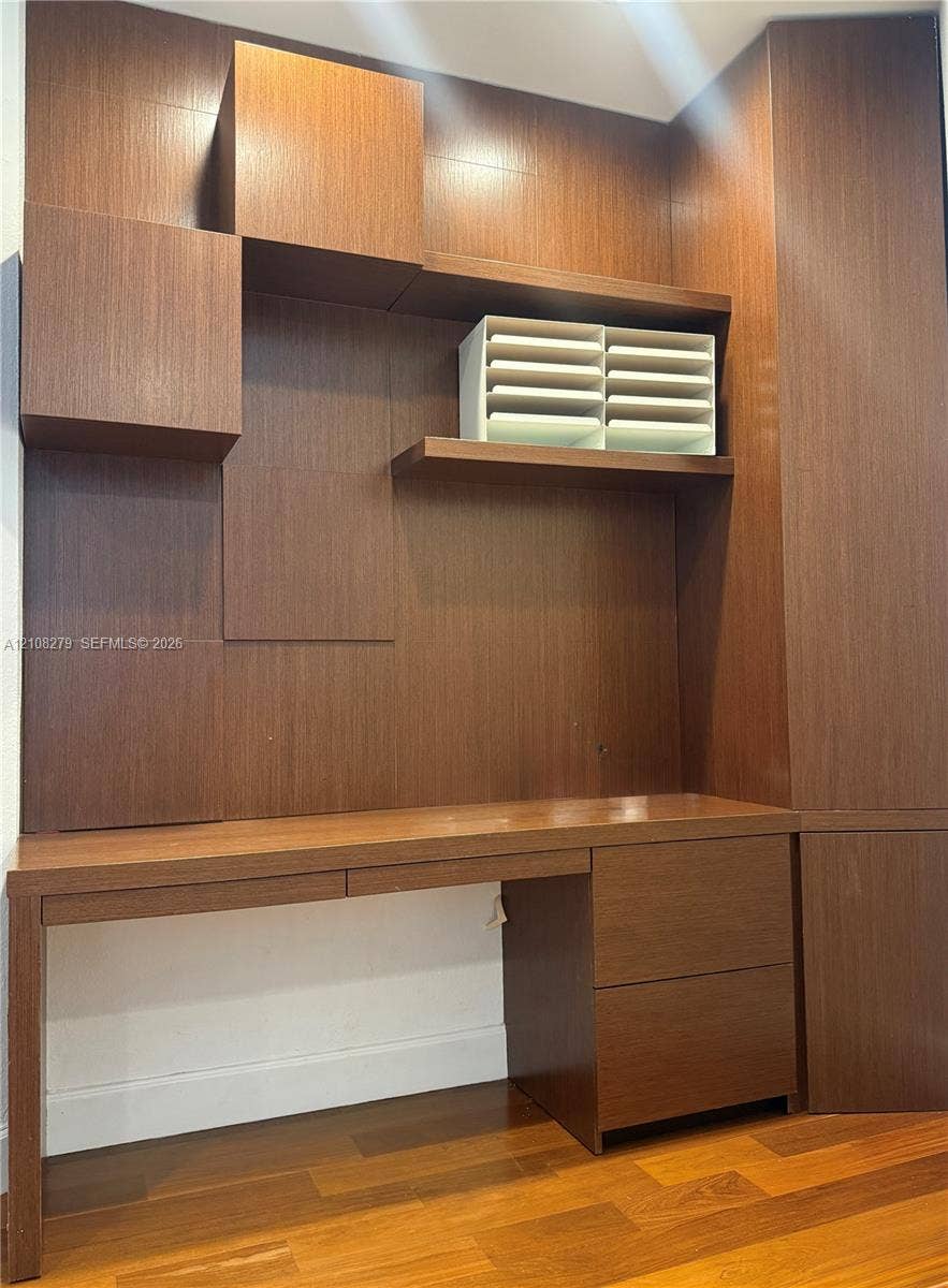 19424 39th Avenue, Sunny Isles Beach, Sunny Isles Beach, FL 33160 Custom built-in wood cabinetry featuring a desktop surface, integrated storage drawers, shelving, and wood-finish flooring
