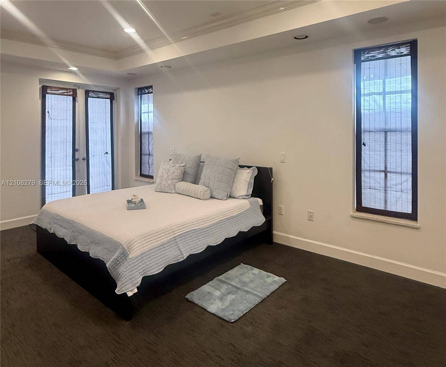 19424 39th Avenue, Sunny Isles Beach, Sunny Isles Beach, FL 33160 Room interior featuring dark carpeting, recessed ceiling lighting, tray ceiling architectural detail, tall windows, and glass-paned double doors