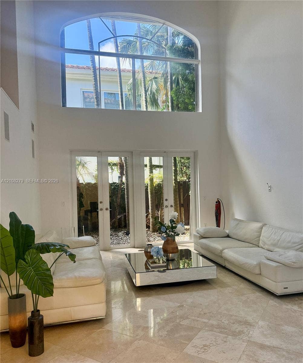 19424 39th Avenue, Sunny Isles Beach, Sunny Isles Beach, FL 33160 Double-height living area featuring floor-to-ceiling arched windows, stone tile flooring, and dual sets of glass-paned doors