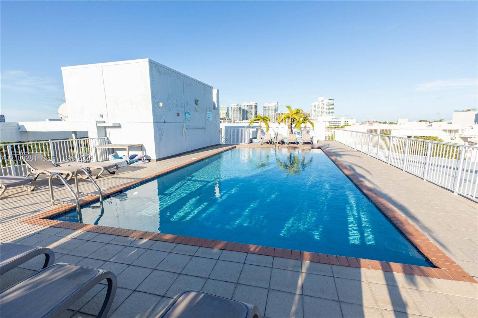 Rooftop swimming pool featuring a tiled deck, metal perimeter railings, and integrated pool stairs