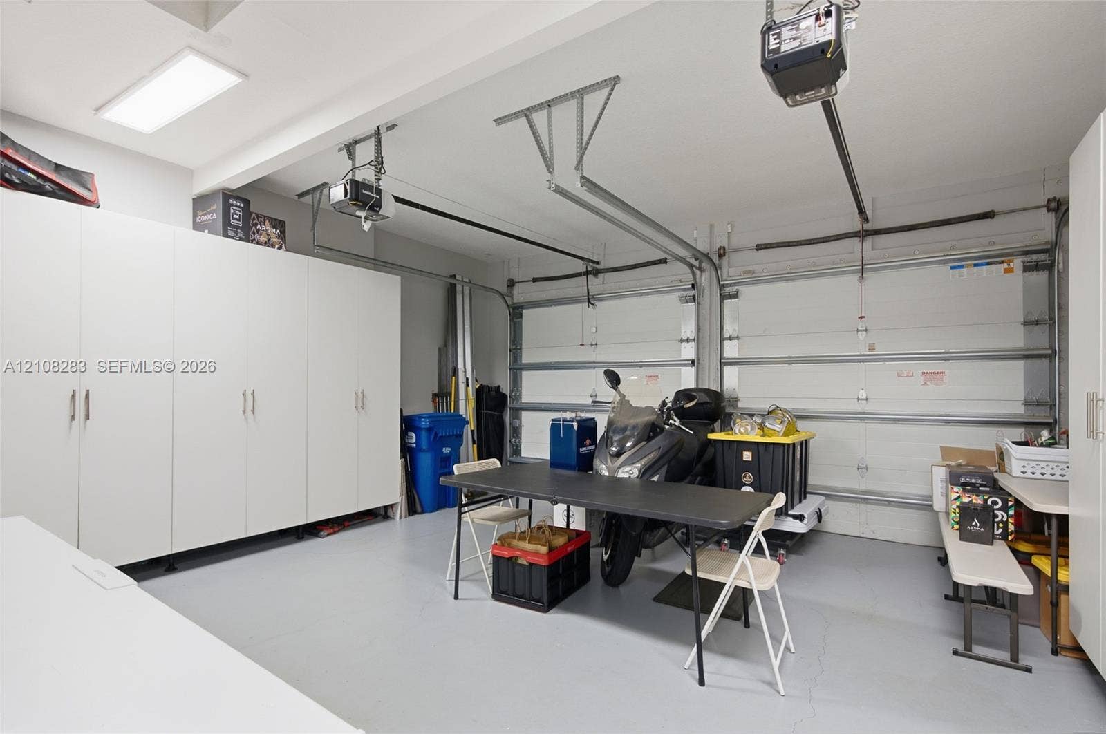 15215 SW 176th Lane, Miami, FL 33187 Two-car garage featuring a sealed concrete floor, dual automatic garage door openers, and extensive floor-to-ceiling built-in white cabinetry