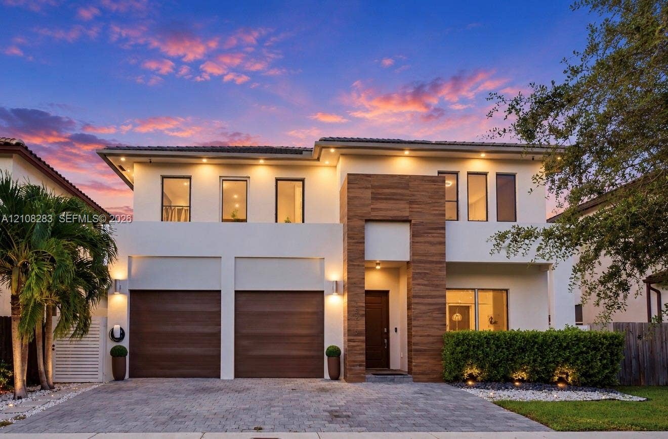 15215 SW 176th Lane, Miami, FL 33187 Two-story contemporary exterior featuring stucco siding, vertical wood-finish accents, dual-car garage, recessed exterior lighting, and a paved stone driveway