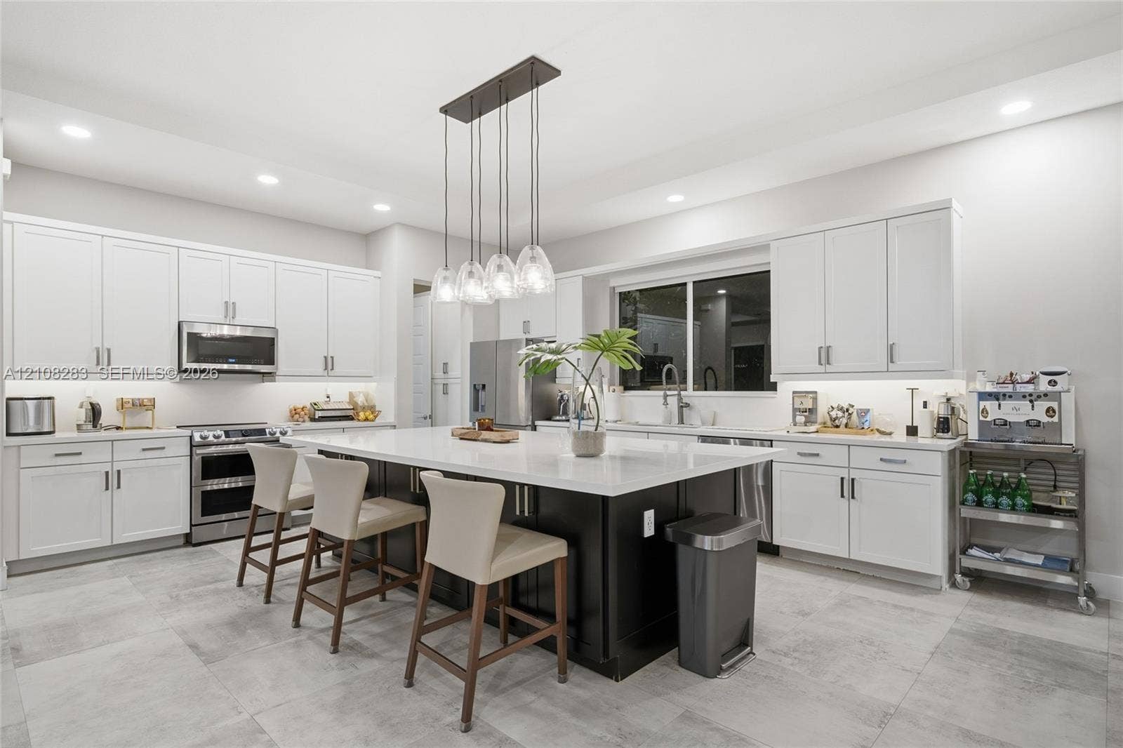 15215 SW 176th Lane, Miami, FL 33187 Kitchen featuring white Shaker-style cabinetry, a central island with a contrasting dark base and stone countertop, stainless steel appliances, recessed ceiling lighting, and tile flooring