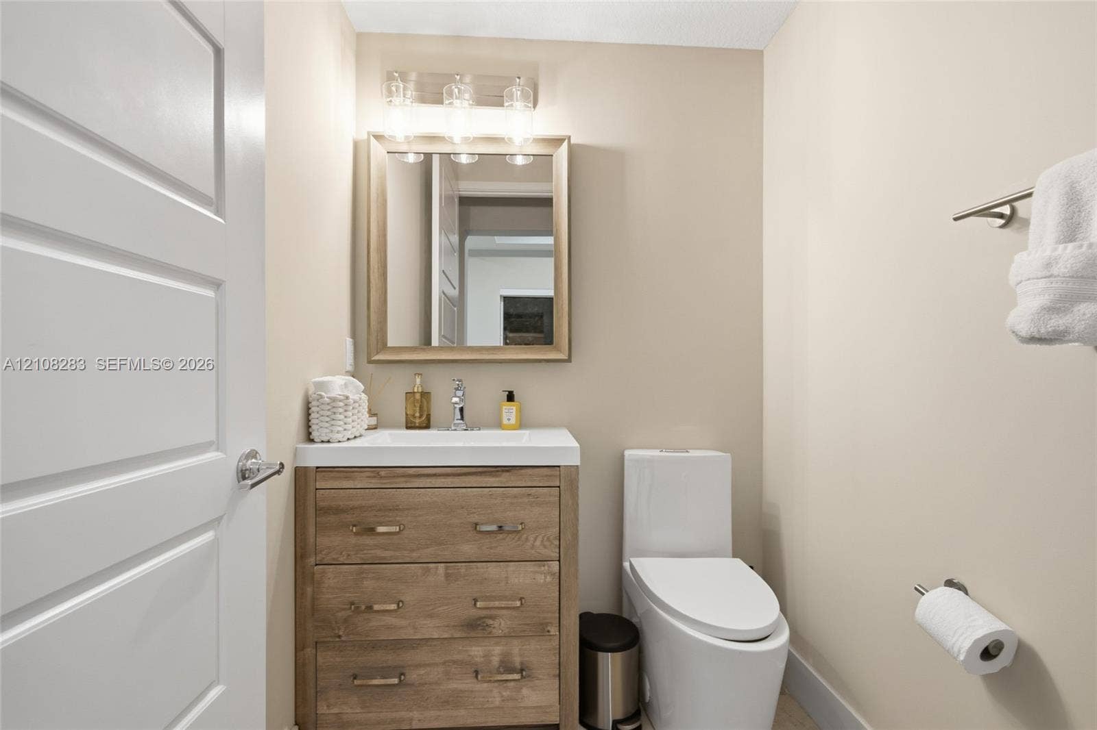 15215 SW 176th Lane, Miami, FL 33187 Bathroom featuring a wood-finish vanity with a rectangular sink, wall-mounted light fixture, framed mirror, and elongated dual-flush toilet