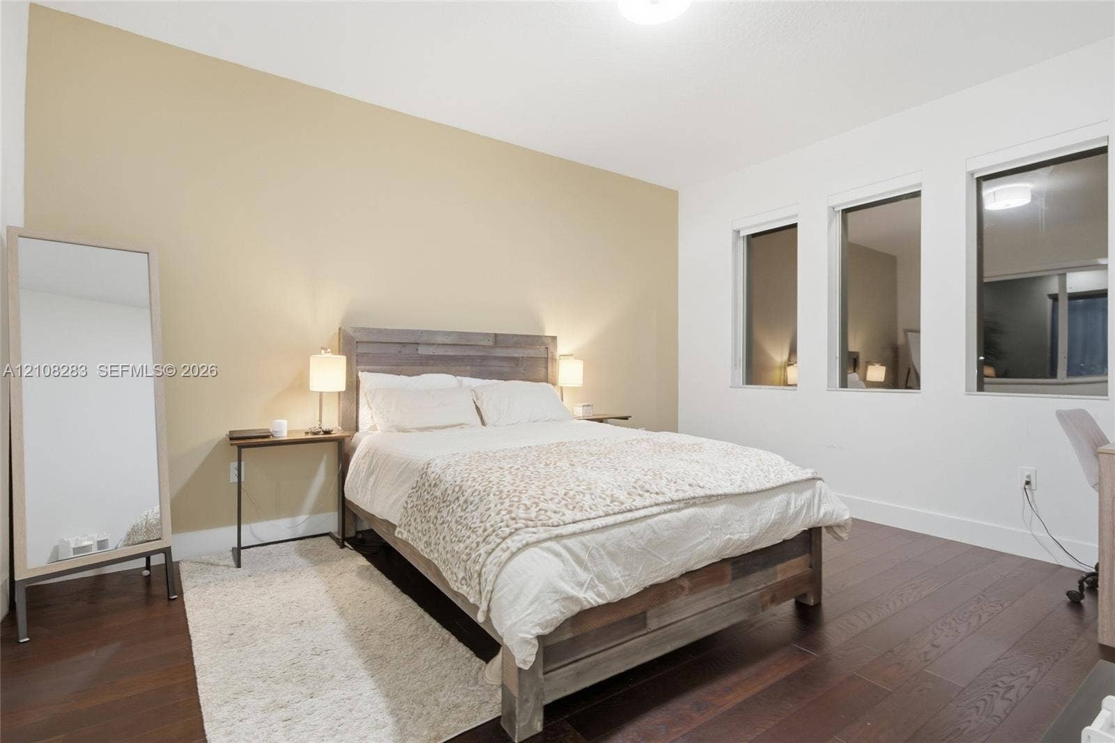 15215 SW 176th Lane, Miami, FL 33187 Room featuring wood-finish flooring, three vertical windows, and a neutral-toned accent wall