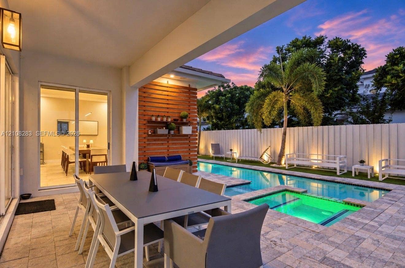 15215 SW 176th Lane, Miami, FL 33187 Covered patio with paver flooring, horizontal slat wood accent wall, built-in shelving, swimming pool with integrated spa, and vertical privacy fencing