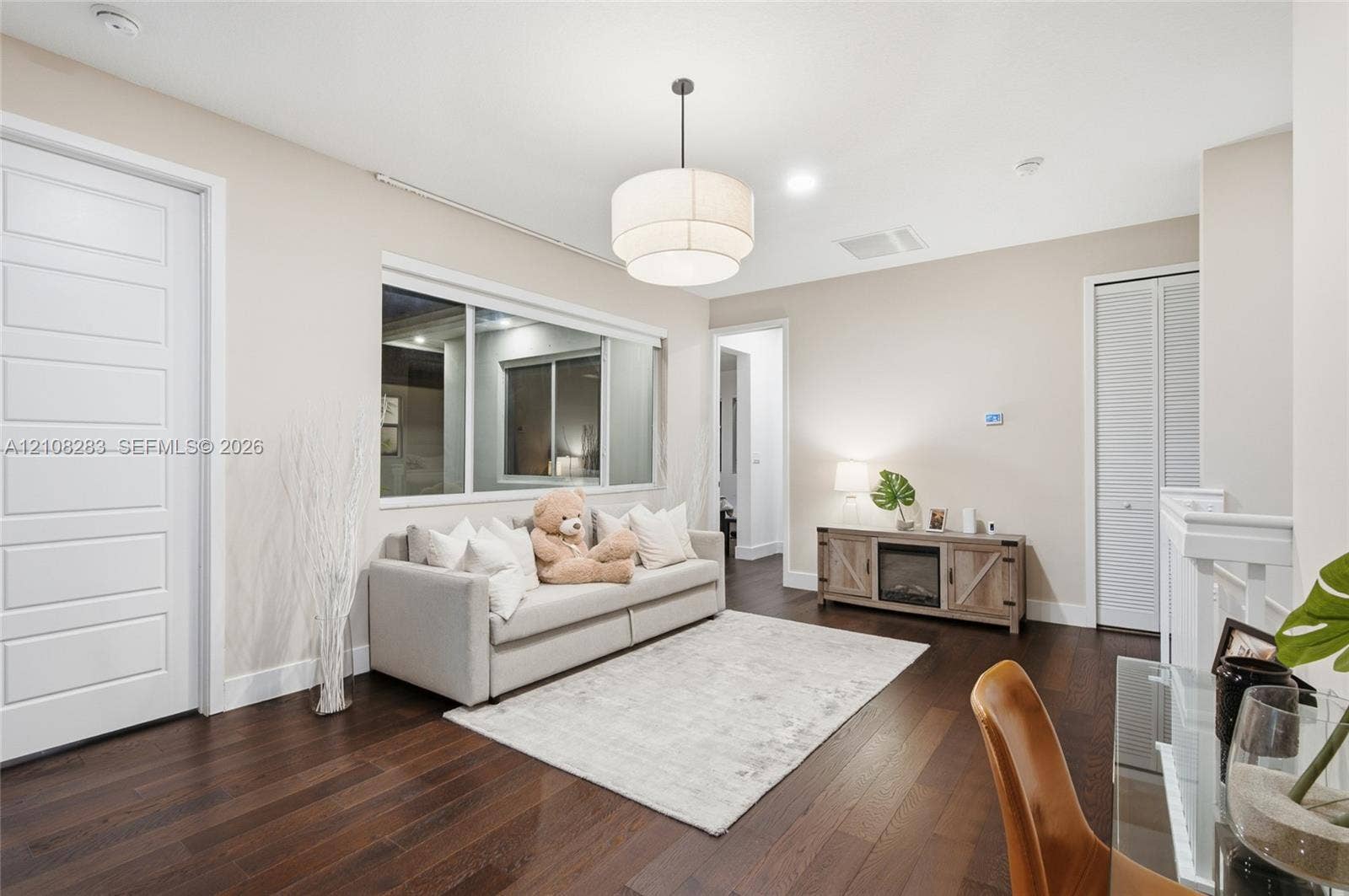 15215 SW 176th Lane, Miami, FL 33187 Dark wood-finish flooring, multi-panel interior door, tiered drum pendant lighting, large sliding window, and louvered closet doors