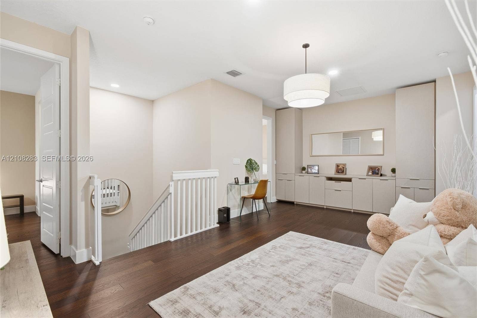 15215 SW 176th Lane, Miami, FL 33187 Dark wood-finish flooring, built-in floor-to-ceiling cabinetry with integrated storage, white spindle staircase railing, and a tiered drum pendant light fixture